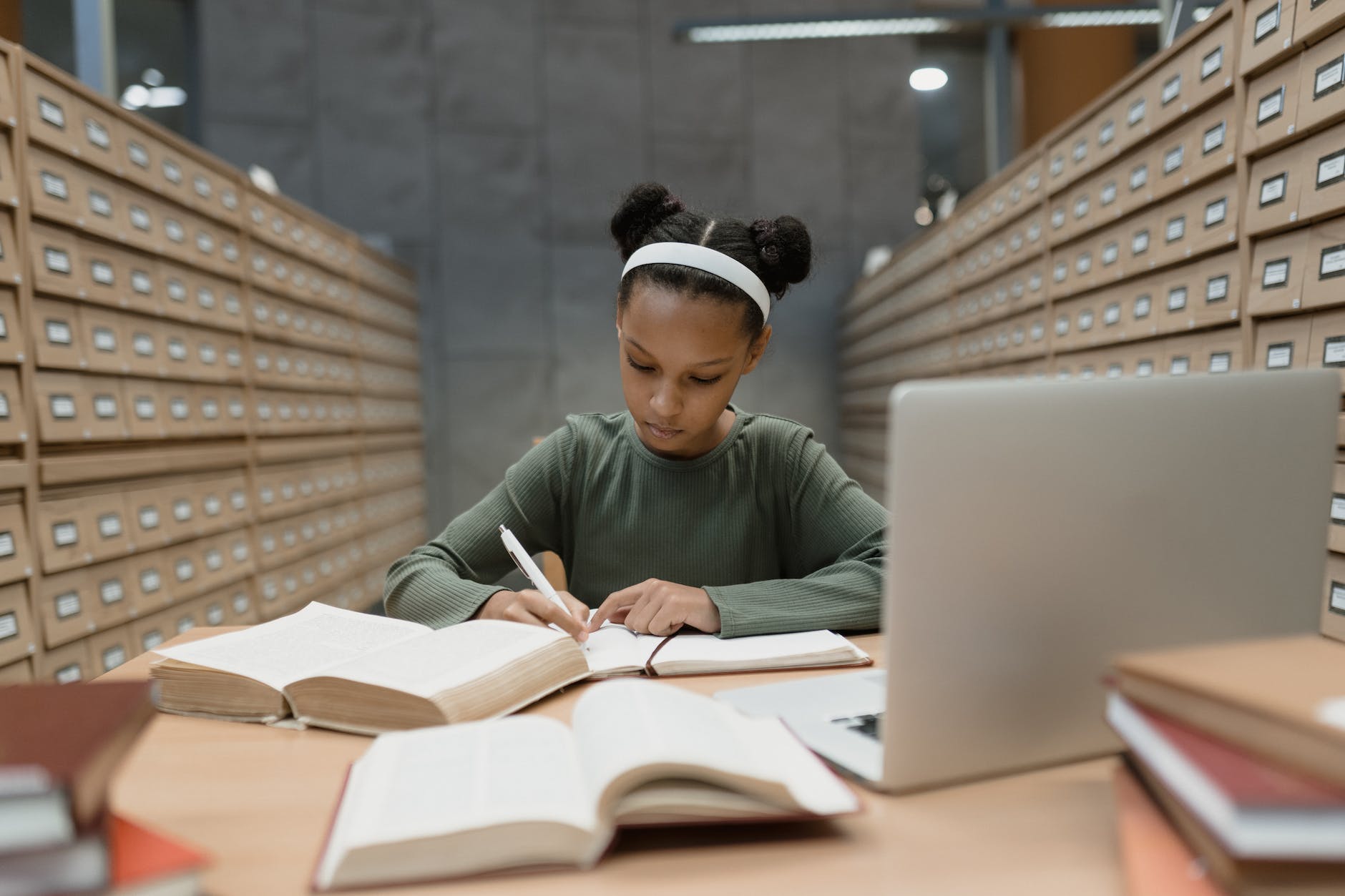 a girl sitting at a desk writing on a notebook